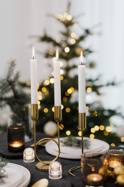 Free A stylish Christmas table with candles and a blurred Christmas tree in the background. Stock Photo