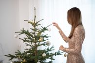 优雅的女人在冬天用装饰品装饰室内的圣诞树
