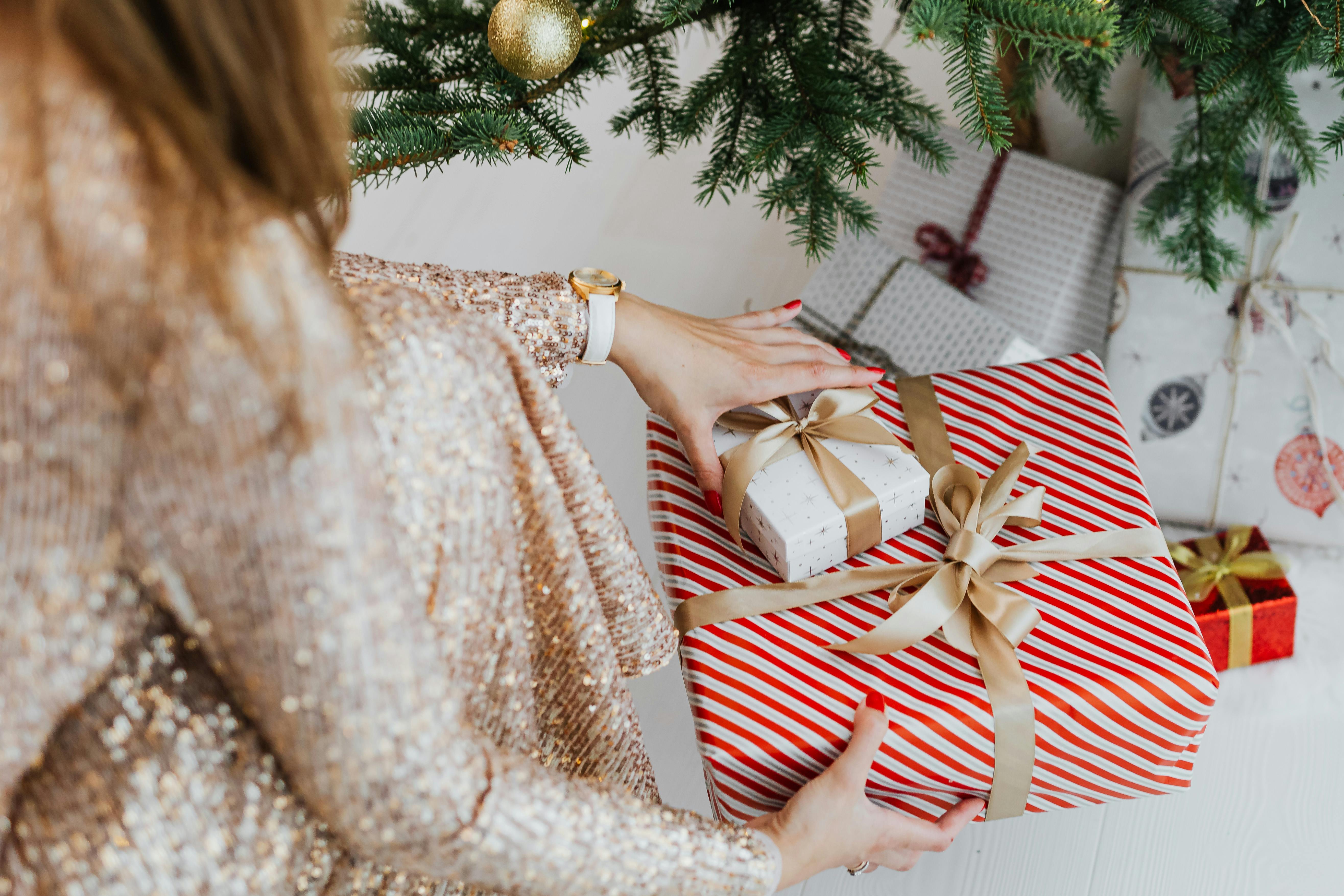 woman putting gifts under christmas tree