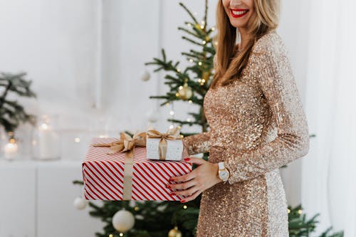 Free Woman in Brown Long Sleeve Dress Holding Red and White Polka Dot Gift Box Stock Photo