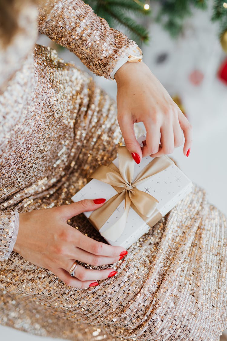 Woman In A Sparkly Gold Dress Unboxing A Present On Christmas 