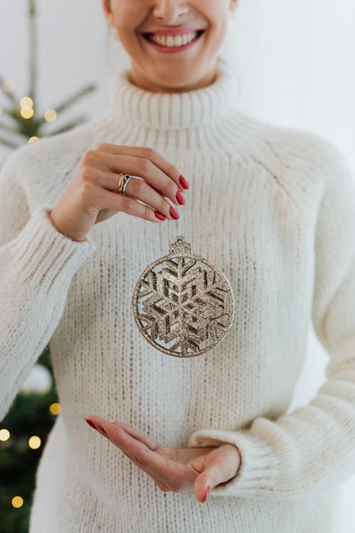 Smiling Woman In White Sweater Holding A Christmas Ornament
