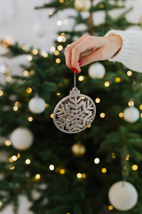 Woman Holding A Silver Christmas Ornament