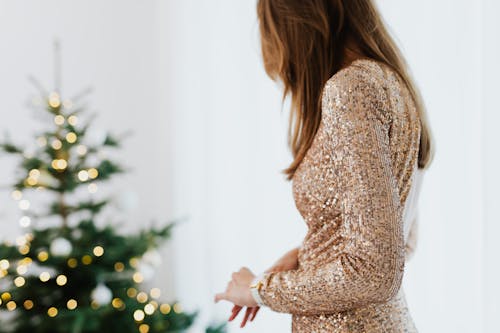 Woman in Golden Glittering Dress Standing Near A Christmas Tree