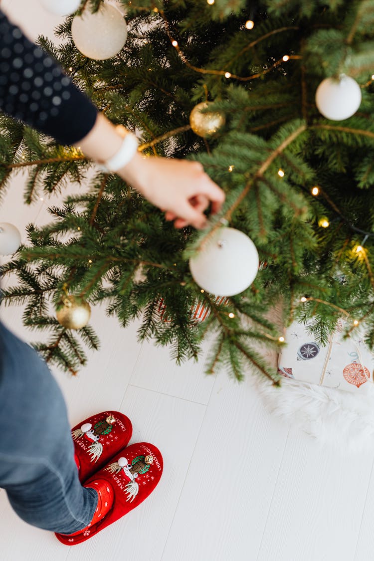 Person Decorating A Christmas Tree With Christmas Balls