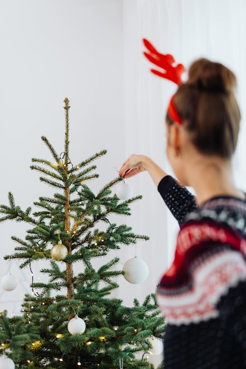 Woman In Knitted Sweater With Headdress Decorating A Christmas Tree