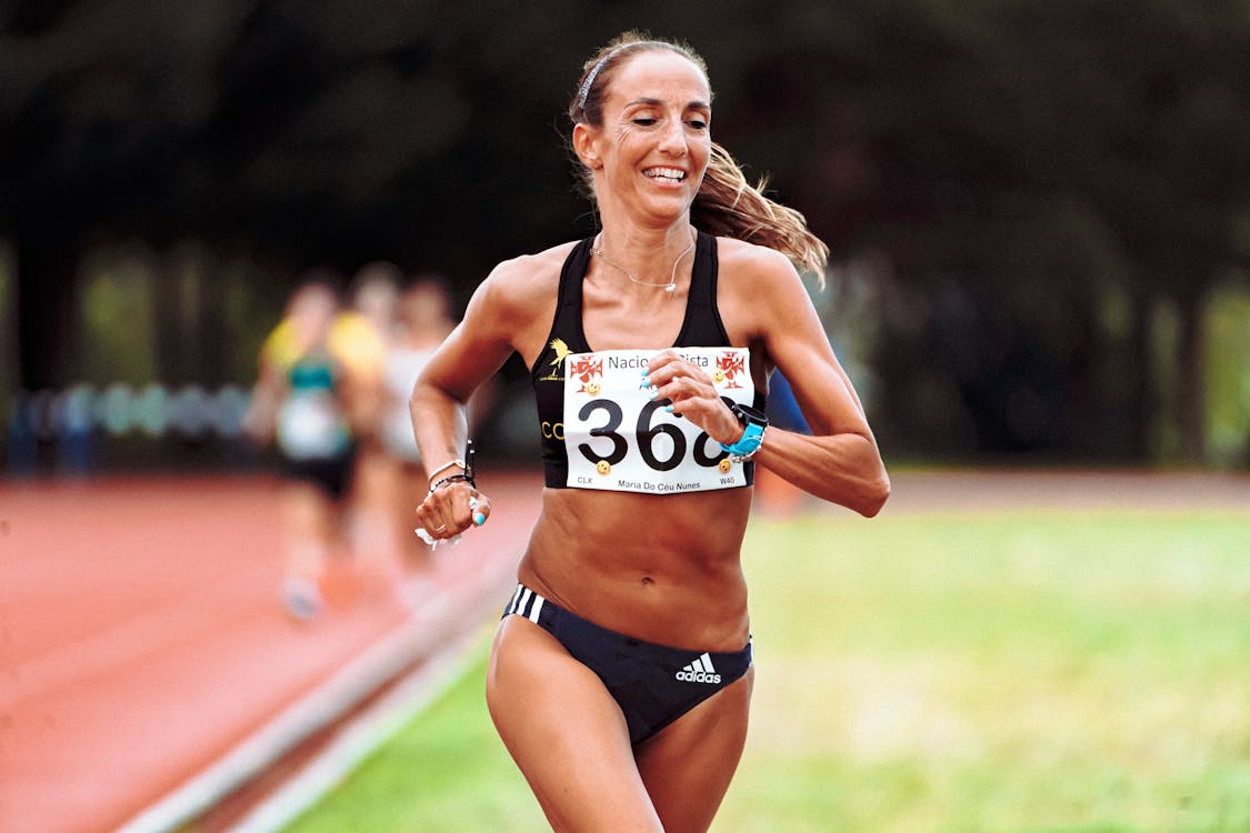 A strong athletic running female athlete on a - Stock