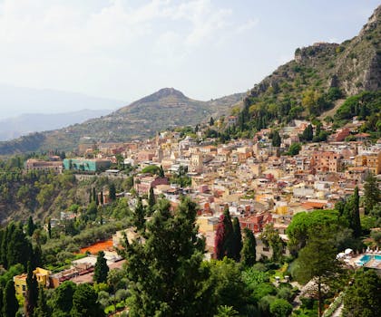 Scenic aerial view of Taormina, Sicily, showcasing vibrant buildings and lush greenery.