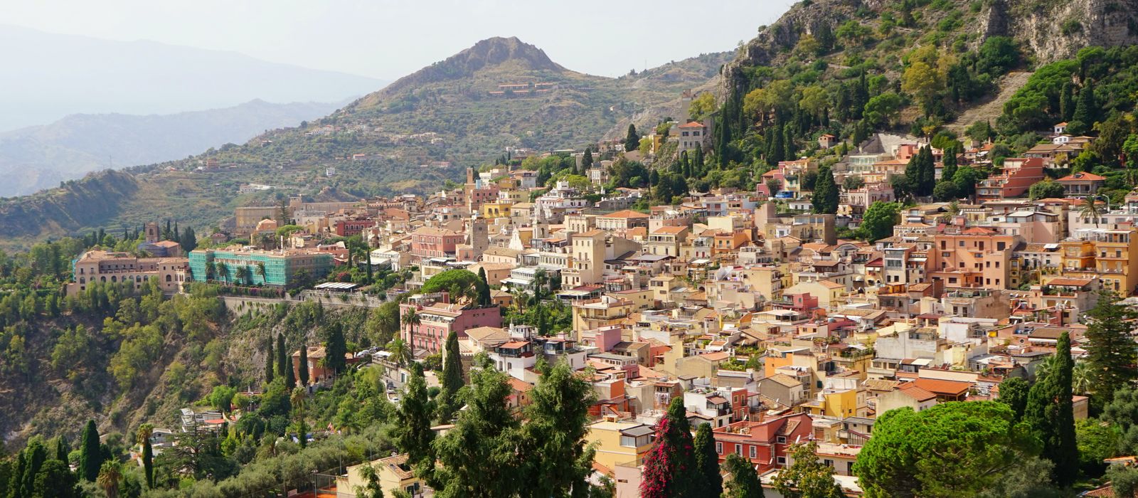Scenic aerial view of Taormina, Sicily, showcasing vibrant buildings and lush greenery.
