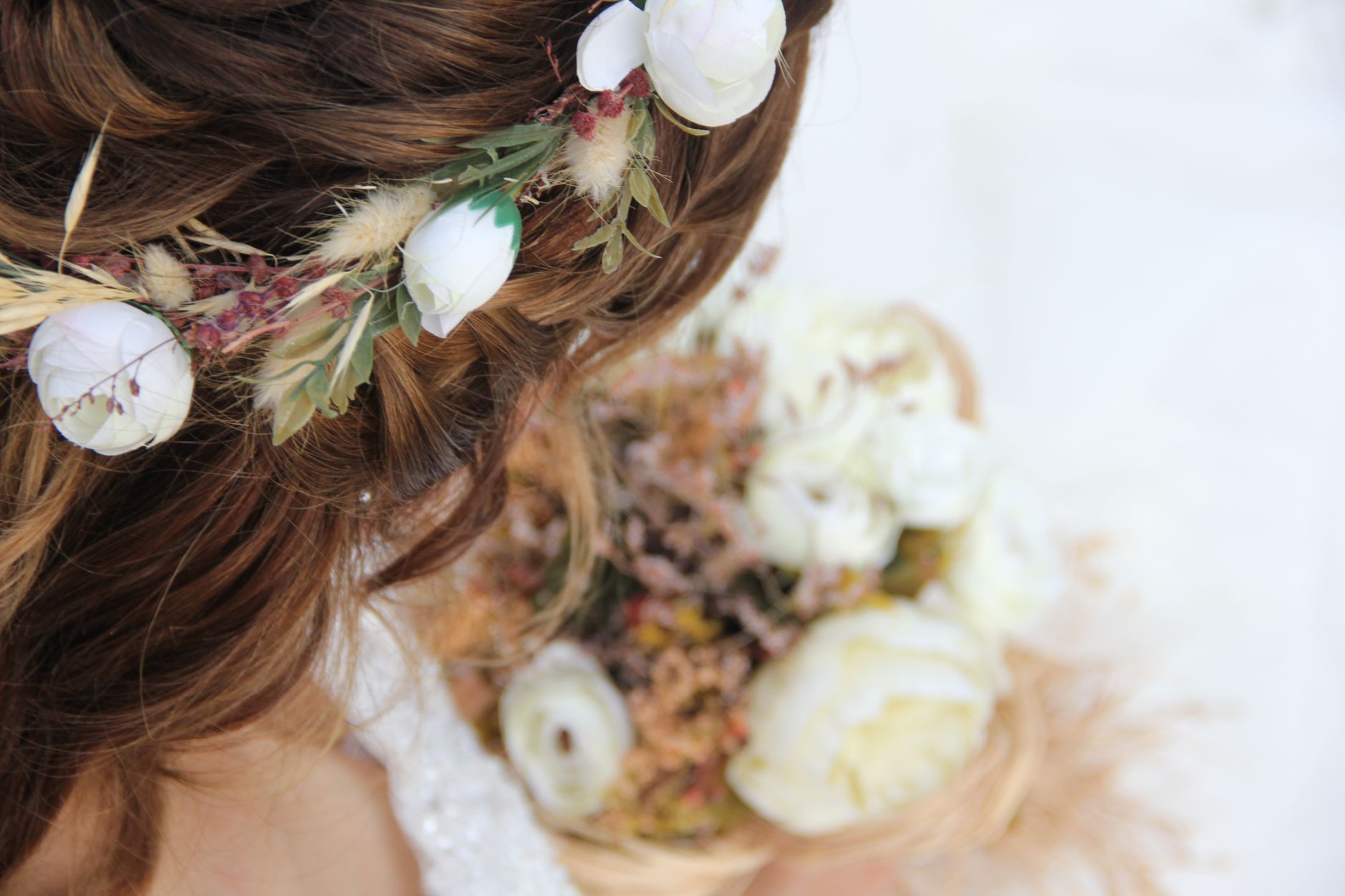 close-up of bride with a romantic braided crown hairstyle, small pearl pins scattered through the plaits and a few tiny fresh white blossoms woven in, wearing a lace-back wedding gown, soft natural li