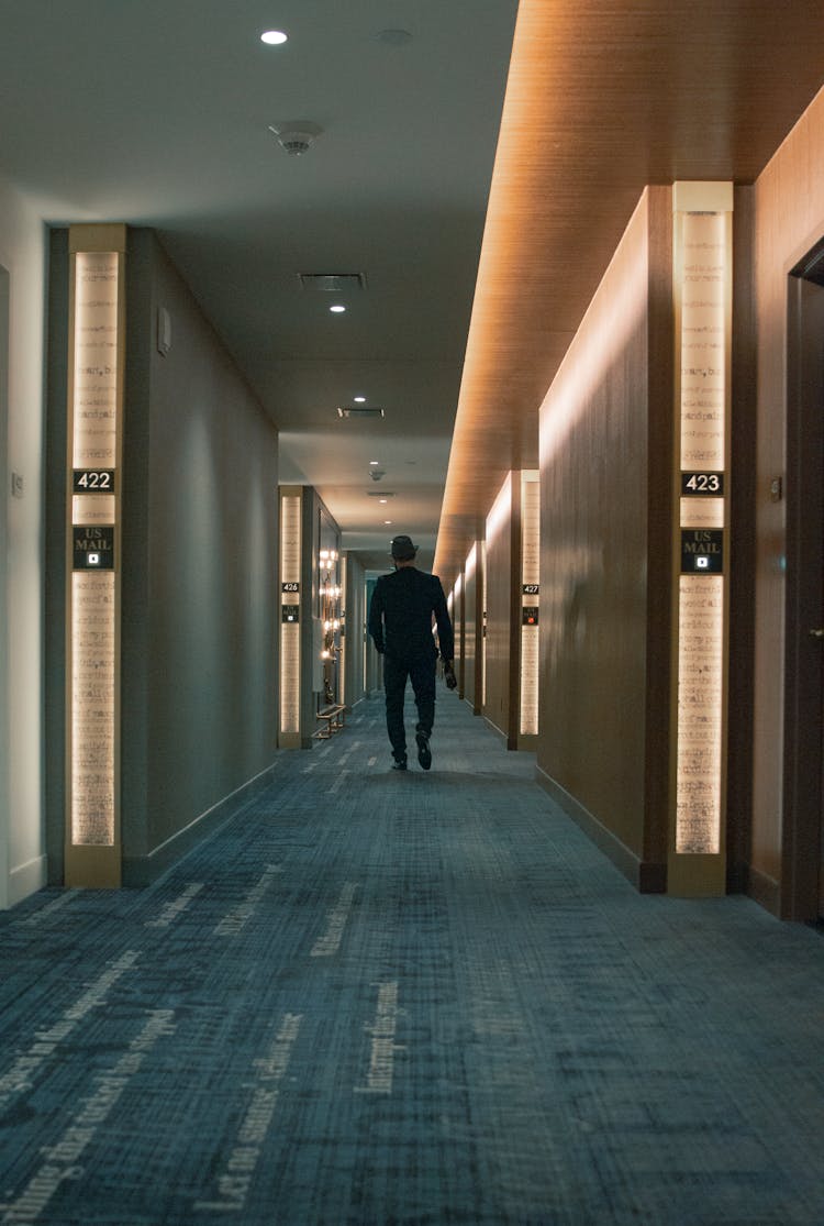 Back View Of A Person Walking In Hotel Hallway