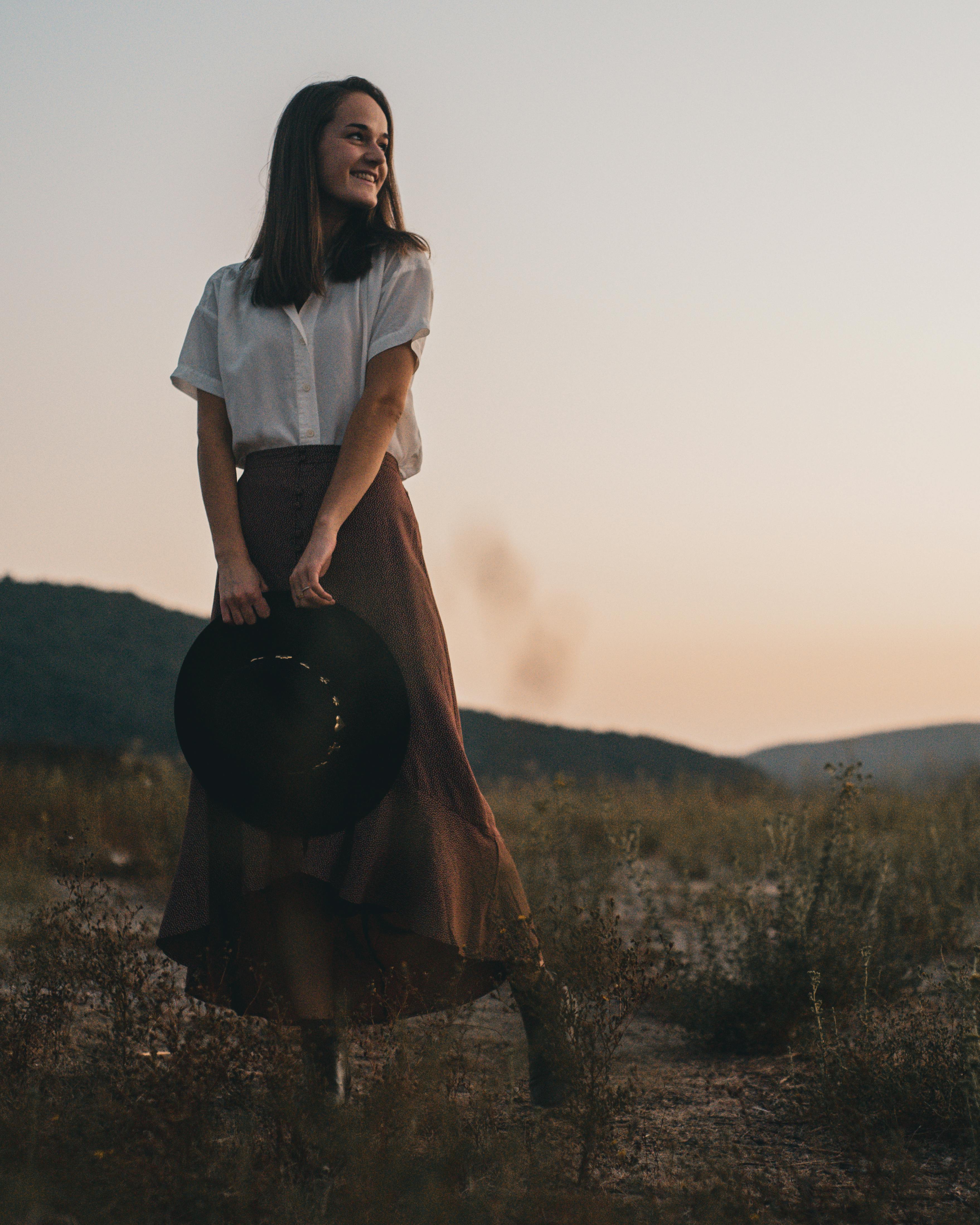 smiling woman in white top and brown skirt posing