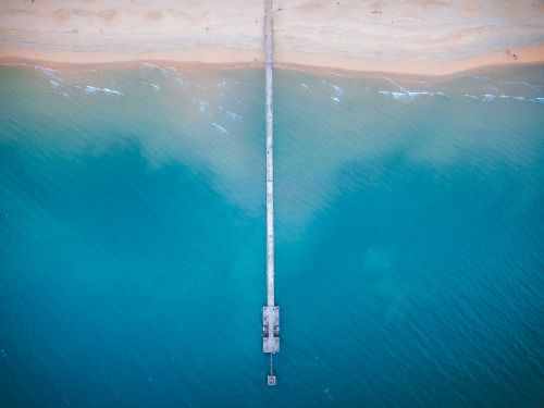 Free Aerial view of platform leading from shore into water of bright blue calm sea Stock Photo