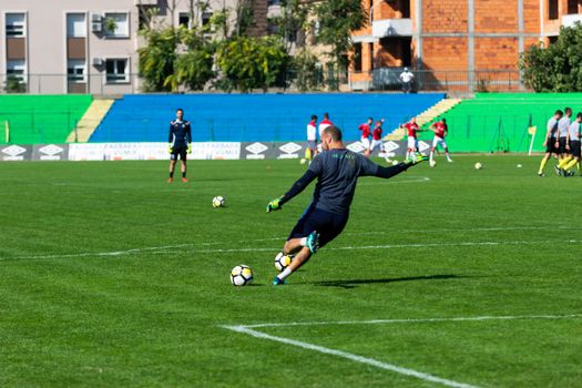 Soccer player in action during practice on a sunny day, kicking the ball on a green field.