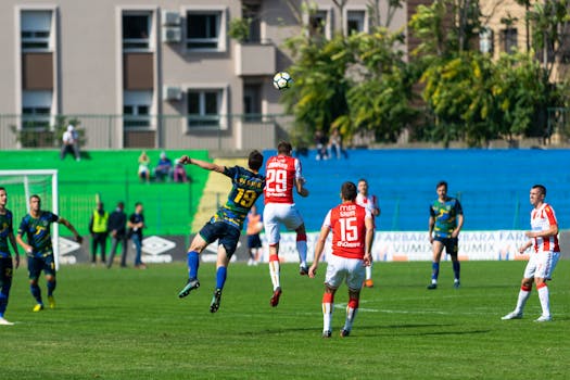 阳光明媚的日子里，身穿红蓝制服的足球运动员在户外展开激烈比赛