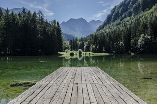 Tranquil lake scene with mountains and dock in Kranj, Slovenia.
