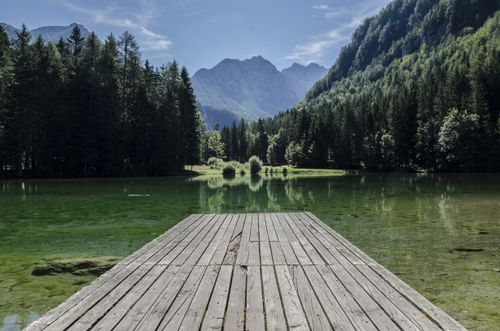 Free Tranquil lake scene with mountains and dock in Kranj, Slovenia. Stock Photo