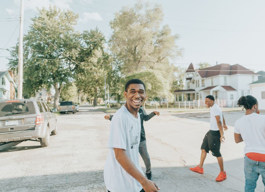 Group of young adults laughing and enjoying a sunny day in an Omaha neighborhood.