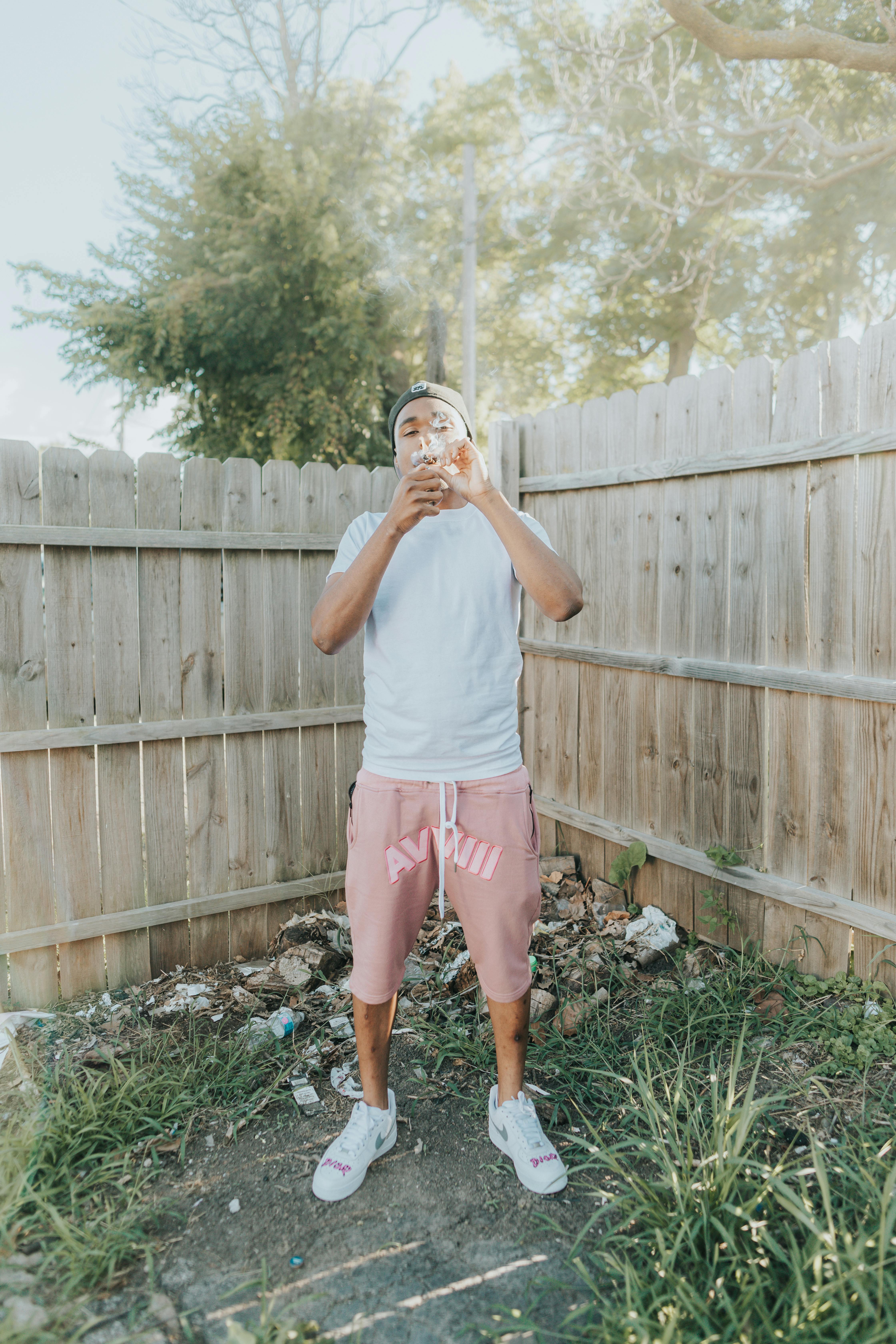 woman in white crew neck t shirt and pink shorts standing on green grass field during