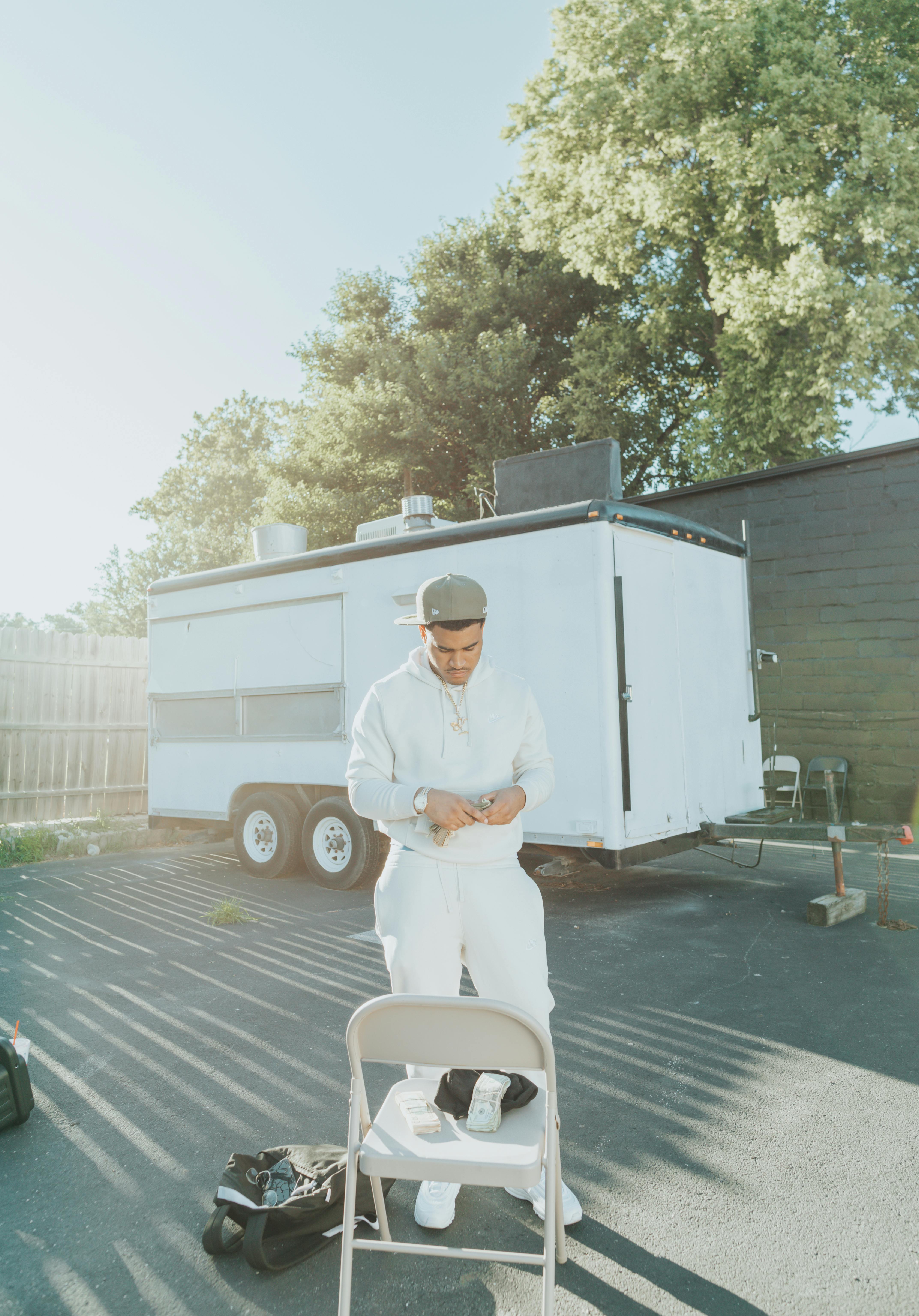 a man in white hoodie and pants counting money