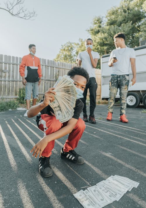 Free Group of African American teens outdoors holding cash, relaxed vibe. Stock Photo