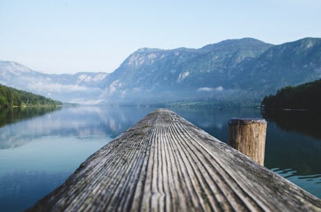 Serene view of a mountain lake from a wooden dock in Radovljica, Slovenia.