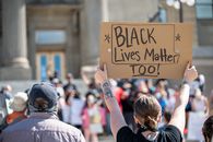 People standing together with cardboard poster during demonstration calling for attention to problem of discrimination against black people