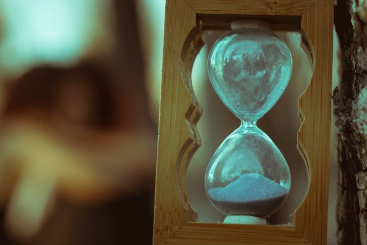 Hourglass with pale blue sand in a wooden frame, close-up