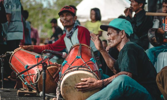 Ethnic male artists in casual apparel playing percussion musical instruments near microphone in concert