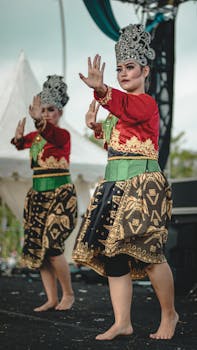 Young barefoot ethnic women in traditional costumes and crowns dancing on stage in concert