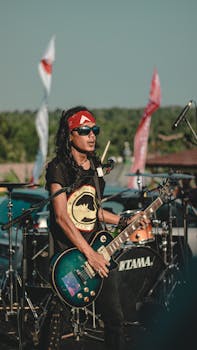 Live outdoor concert featuring a male rock guitarist with a bandana and sunglasses.