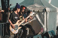 Male rock band guitarists performing live on outdoor stage