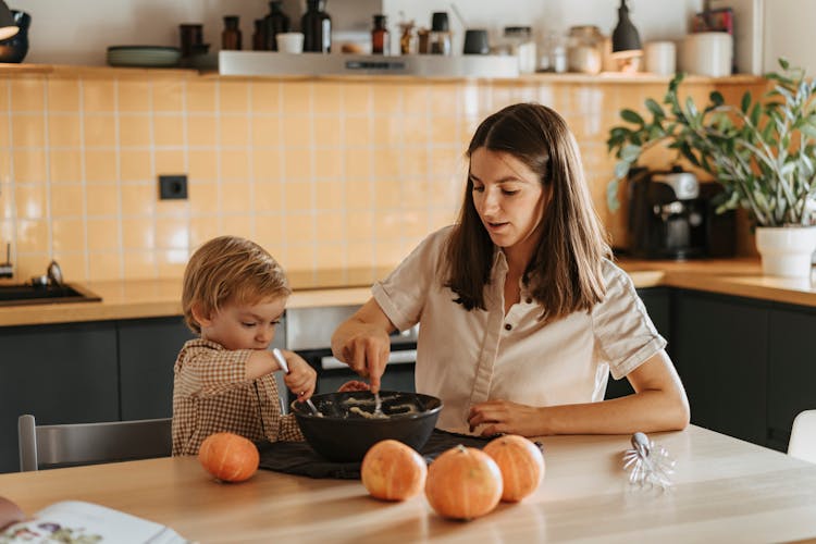 A Mother And Child Mixing A Dough