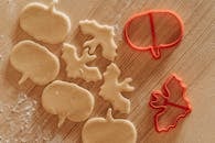 木桌上放着南瓜和蝙蝠形状的饼干面团，配有刀具，非常适合万圣节烘焙