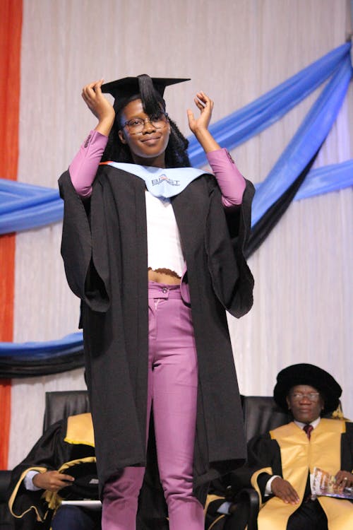 Smart black female teenager in graduation outfit on stage Free