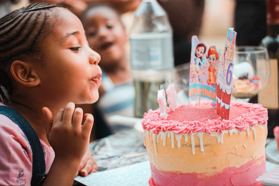 A cheerful birthday card design showing a cute, energetic ram blowing out candles on a giant birthday cake