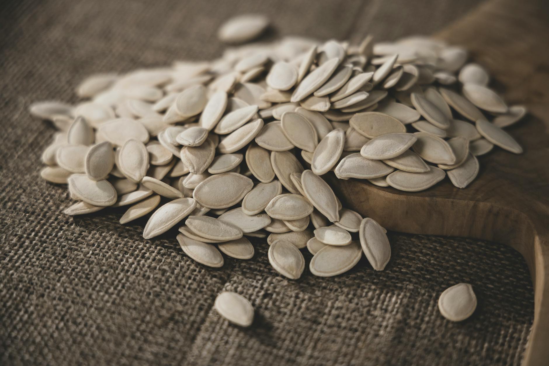 A pile of organic pumpkin seeds on a textured wooden board, showcasing natural textures.