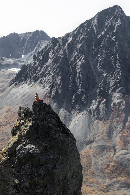 бесплатная Человек в черном пиджаке сидит на скале Стоковое фото