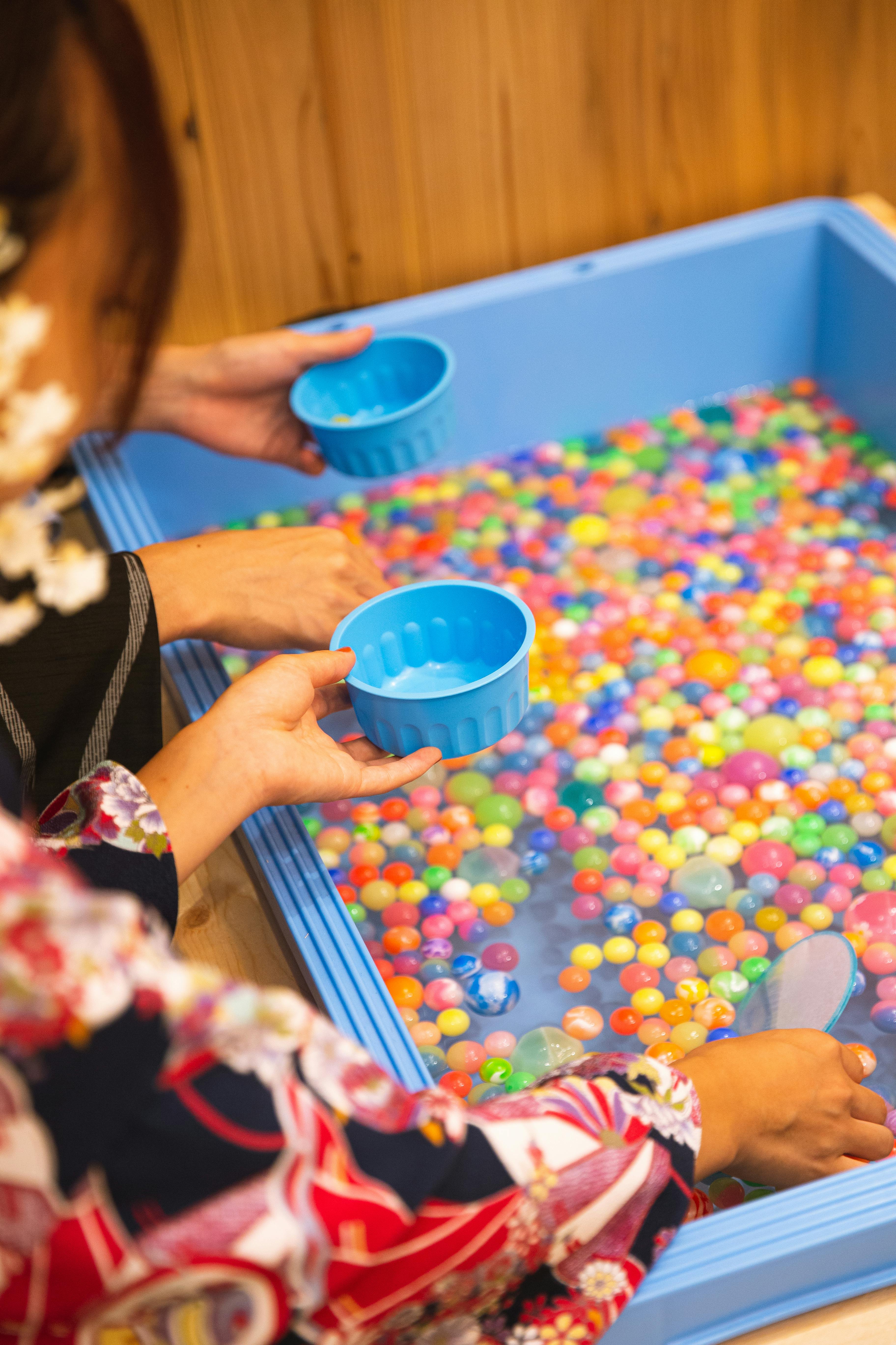 crop faceless women washing fishbowl beads in basin