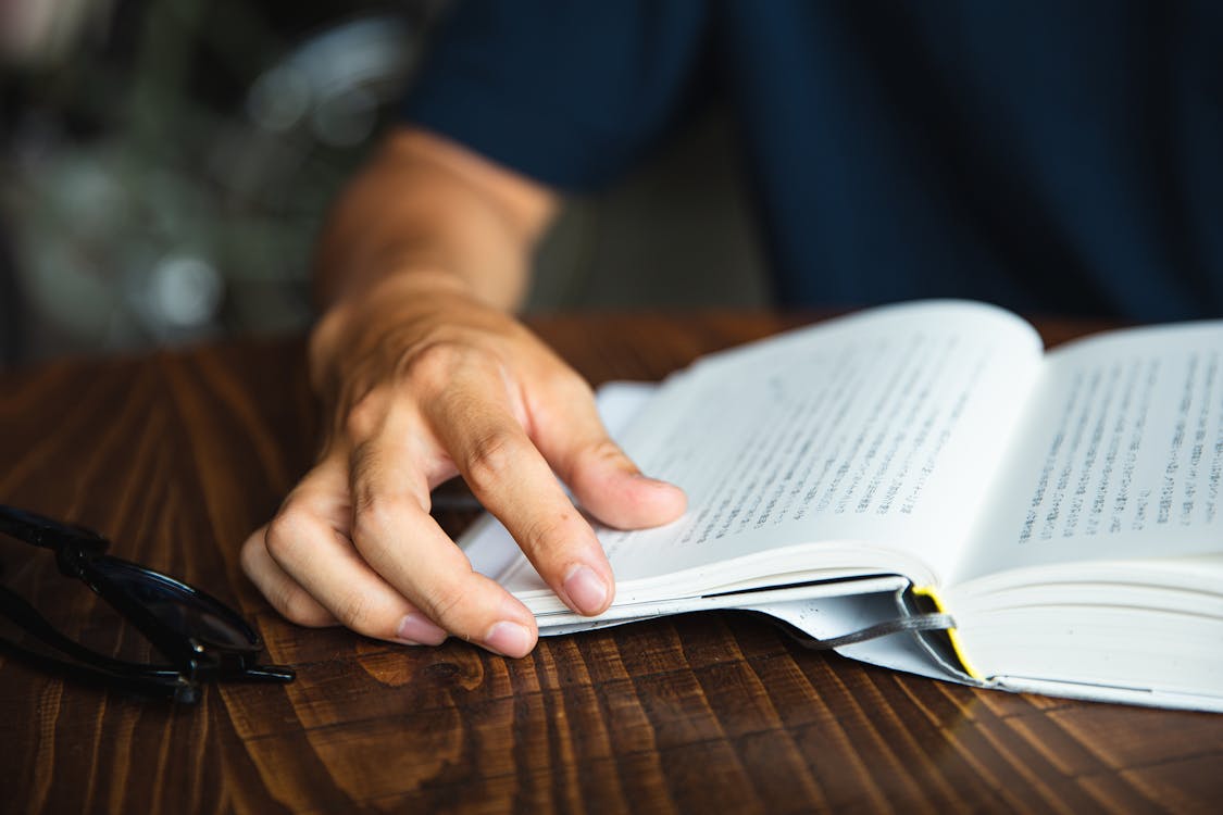 Free Crop unrecognizable man reading book at table Stock Photo