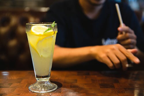 Crop faceless man sitting at table with fresh citrus lemonade