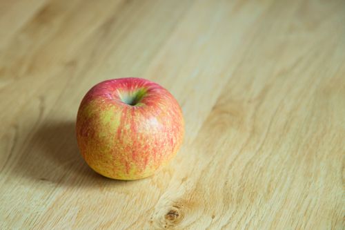 Free From above of delicious whole juicy apple with red and yellow peel on desk Stock Photo