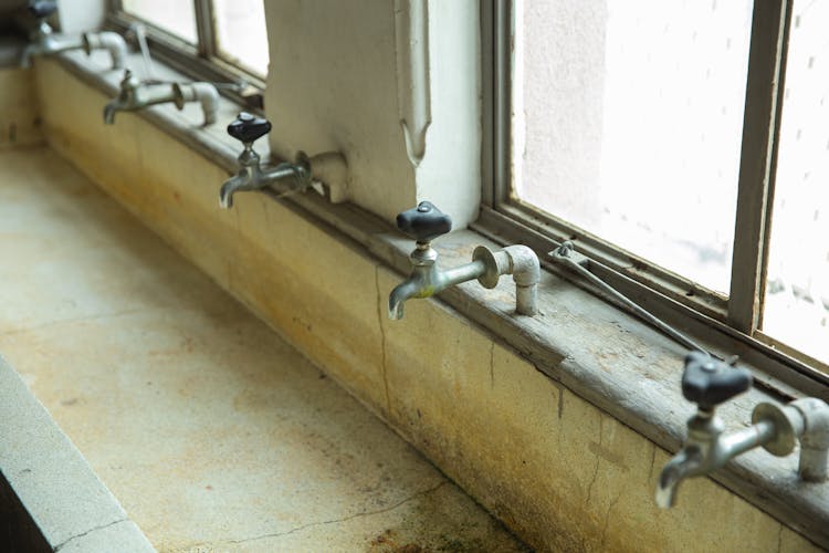 Similar Old Taps Above Weathered Public Sink In Building