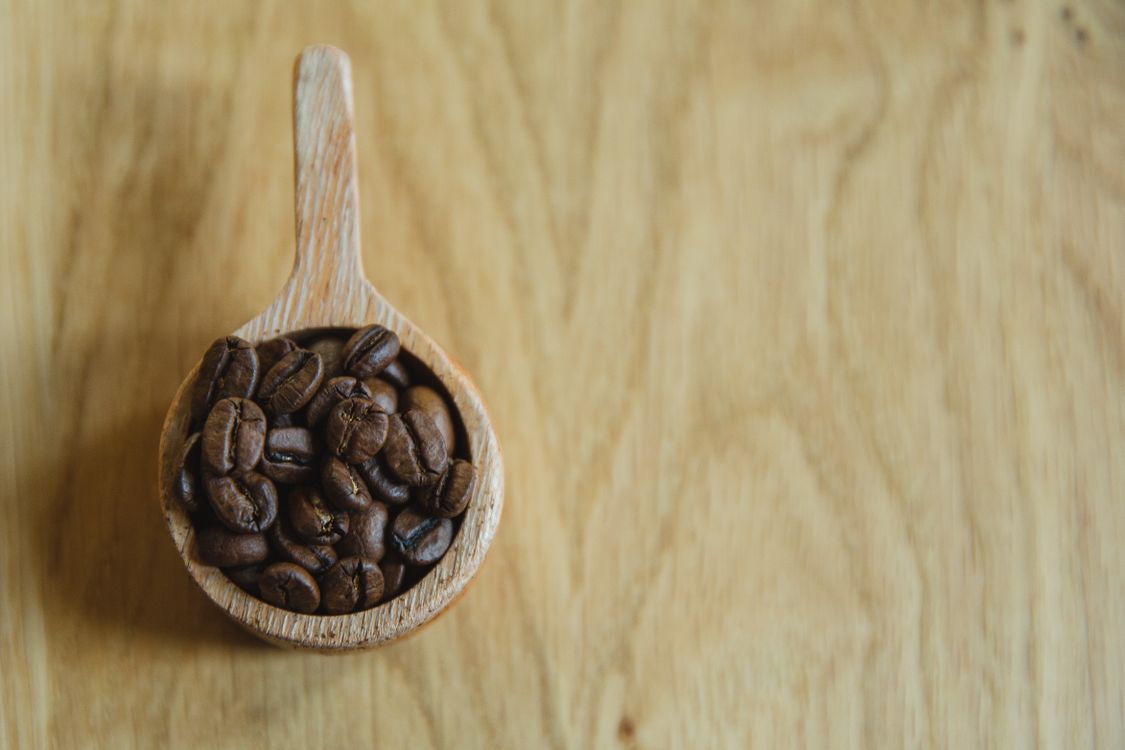 Wooden cup of coffee beans on table · Free Stock Photo