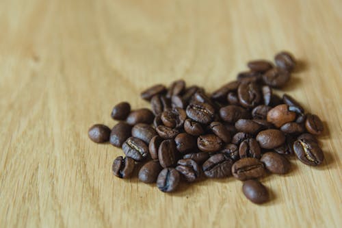 Free Closeup of handful of prepared coffee beans scattered on table before making coffee Stock Photo