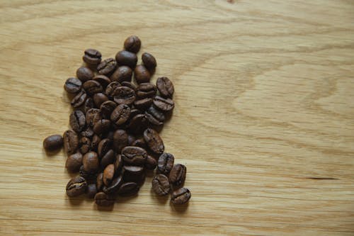 Top view of scattered coffee beans placed on wooden table before making coffee