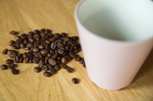 From above of empty mug and coffee beans on wooden table prepared for making coffee