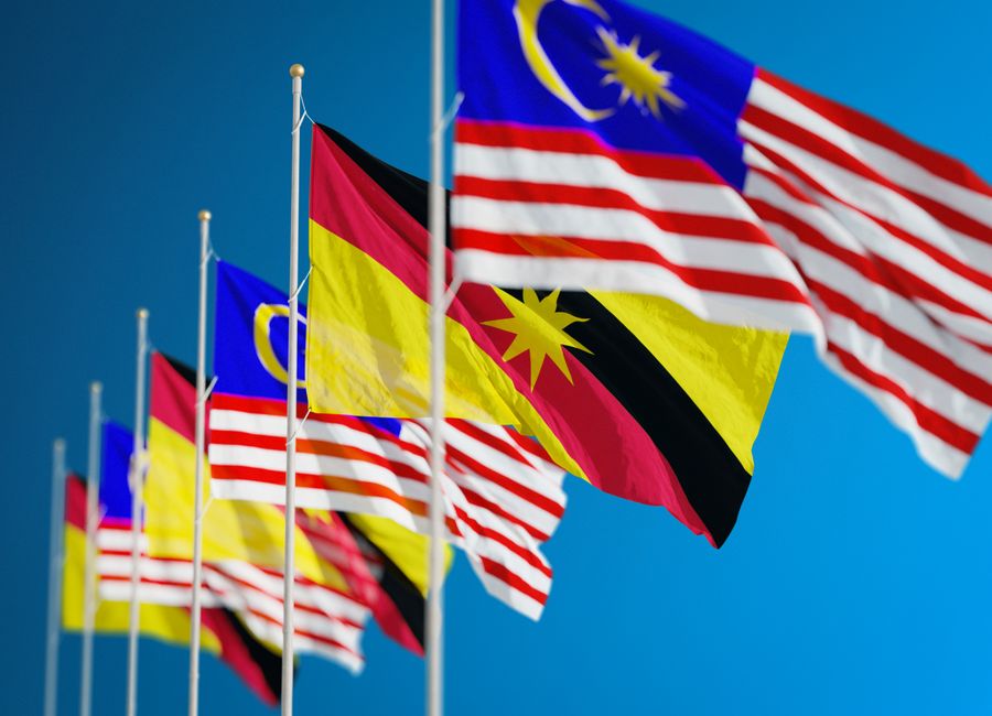 Vibrant display of Malaysian and Sarawak flags symbolizing unity and patriotism against a clear blue sky.