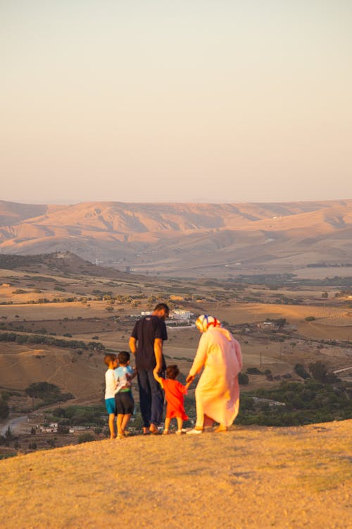 Back view full length Islamic family spending sunny evening on hilltop and enjoying picturesque scenery of hilly spacious terrain