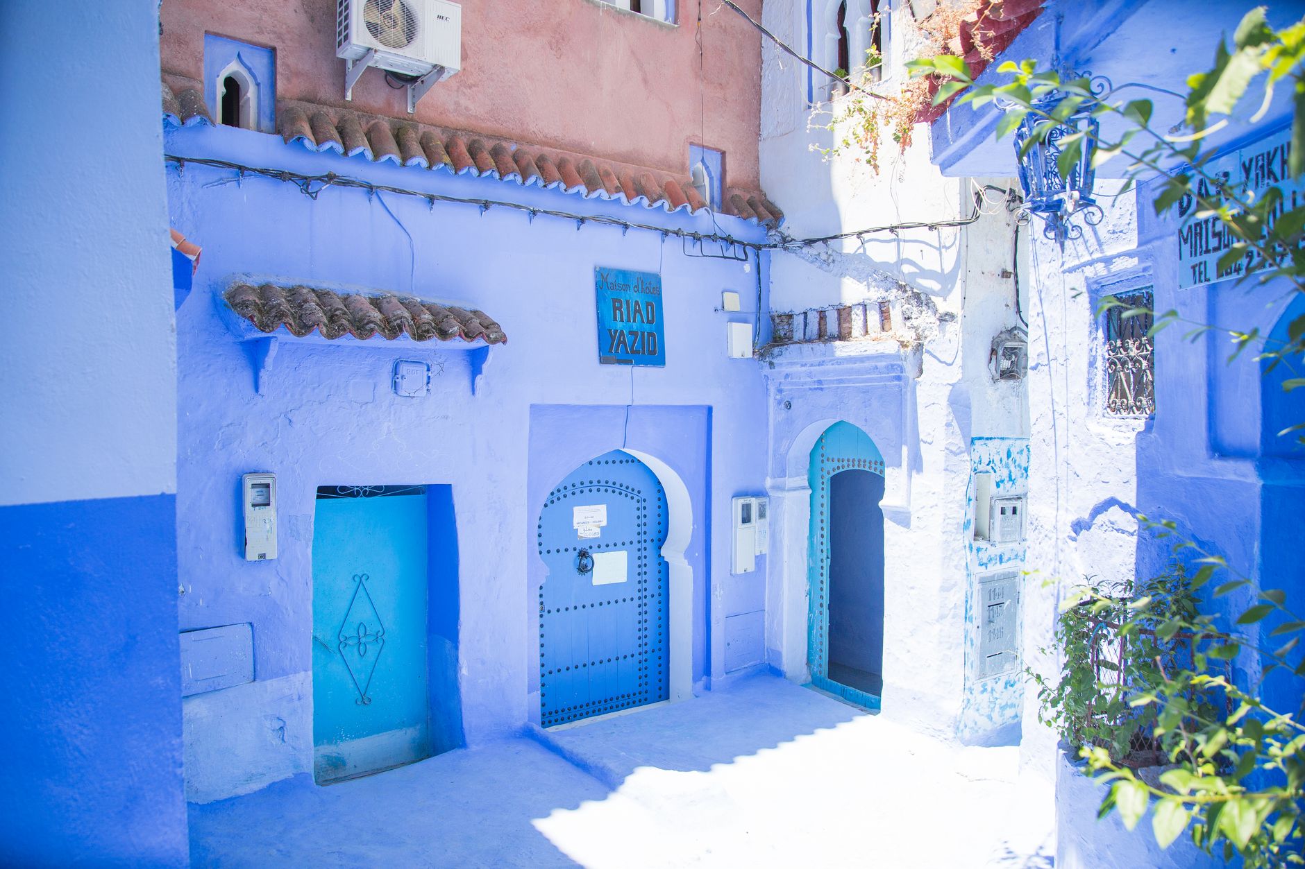 15 Hidden Travel Gems Unexplored Around the World 4 Blue exterior of house with doors located under sunlight on street with green plants in city of Morocco in summer